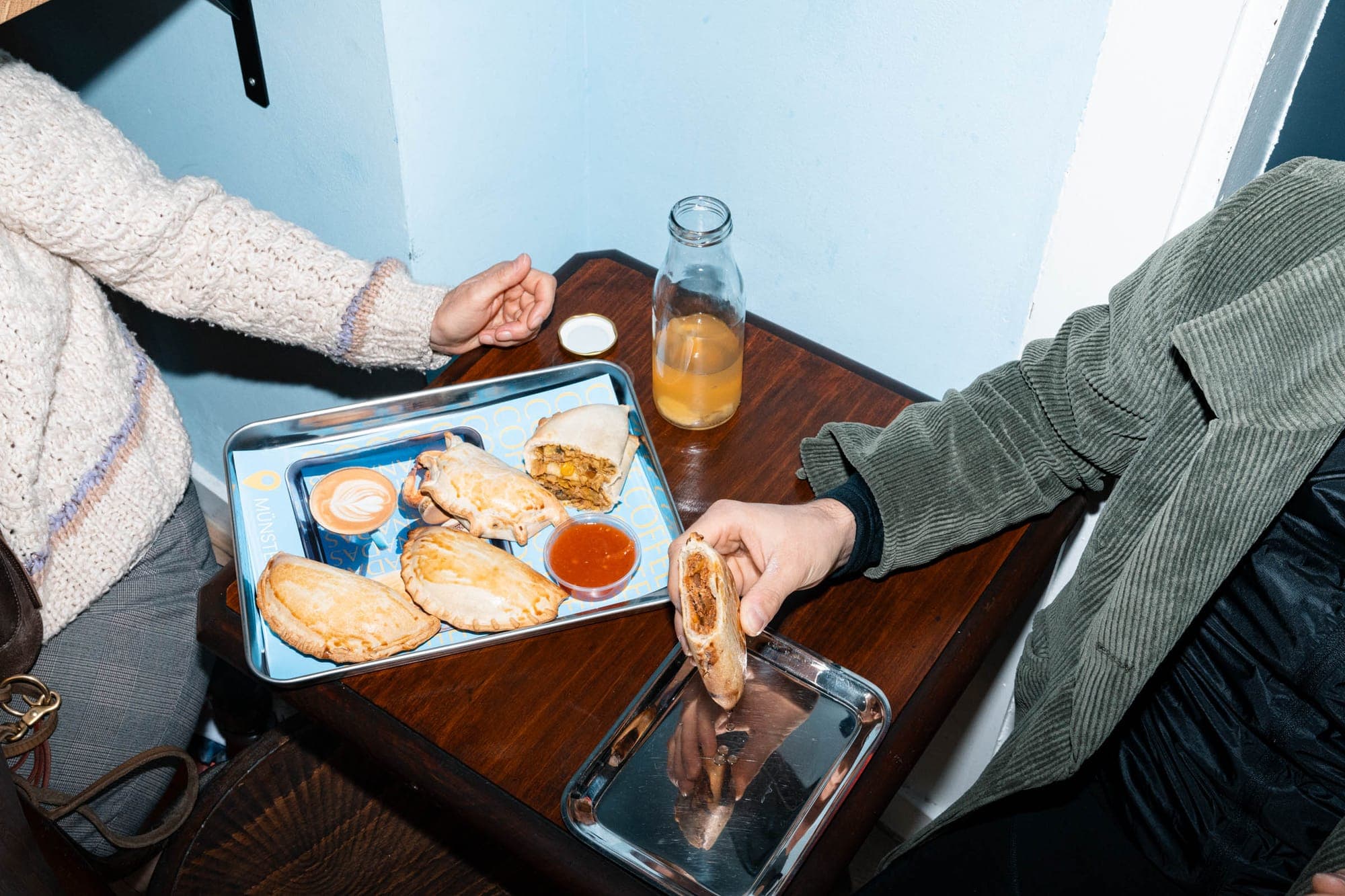 Gäste am Tisch im Store mit Empanadas, Kaffee und Dip