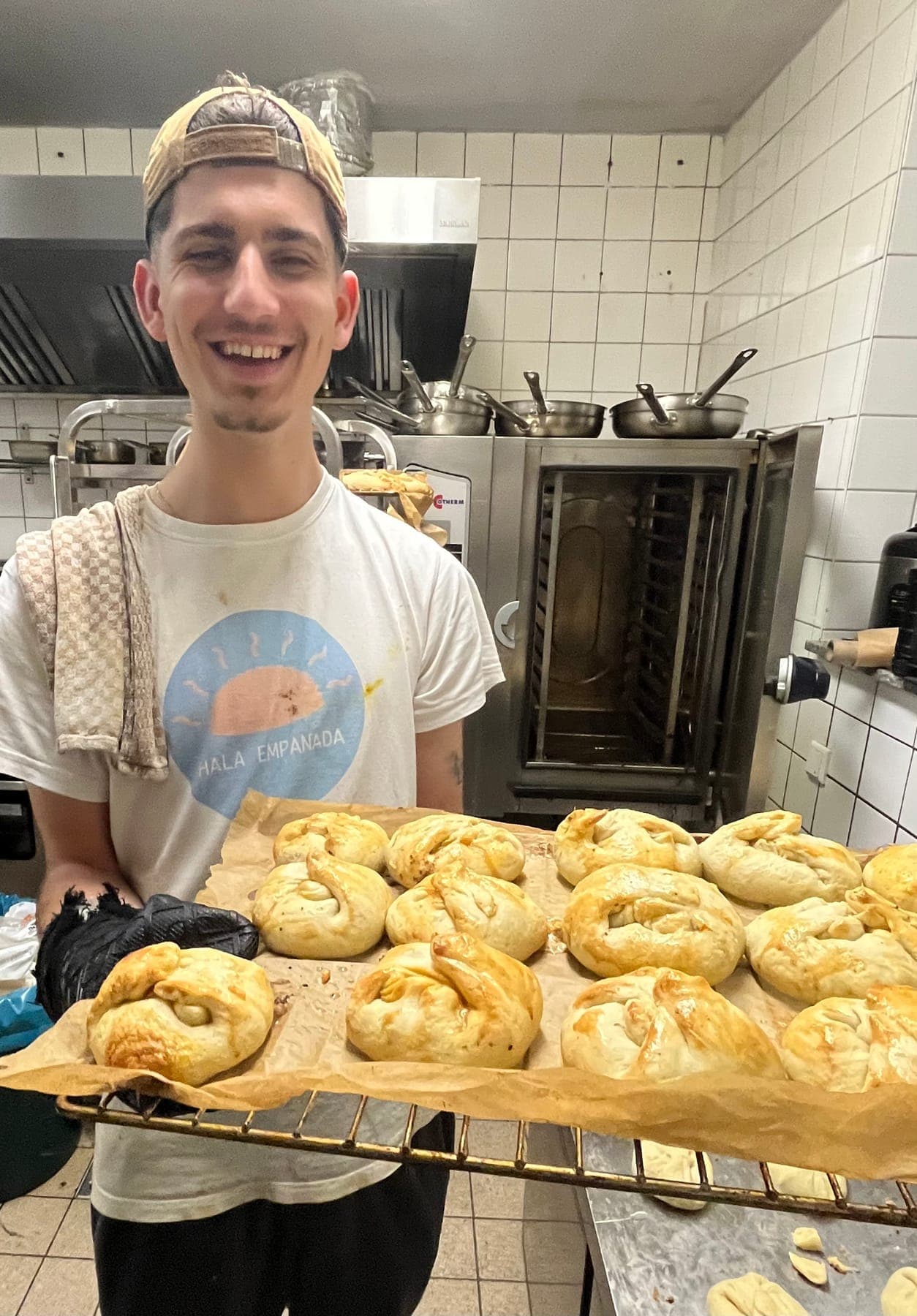 Teammitglied mit einem Blech frisch gebackener Empanadas